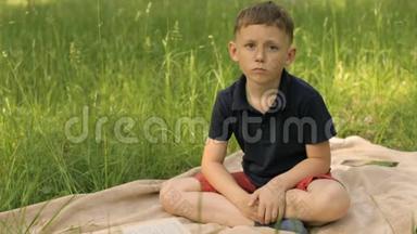 悲伤的男孩<strong>坐在</strong>草地上的<strong>公园里</strong>